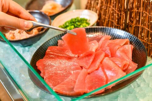 a person is eating a plate of food with meat at Sanco Inn Shizuoka Kitaguchi in Shizuoka