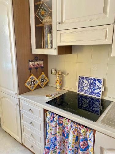 a kitchen with white cabinets and a stove top oven at La Casa del Sole in Corleone