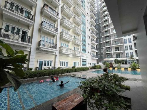 un groupe de personnes dans une piscine située dans un bâtiment dans l'établissement Cozy Iloilo City Condo Room with Shared Pool, à Iloilo