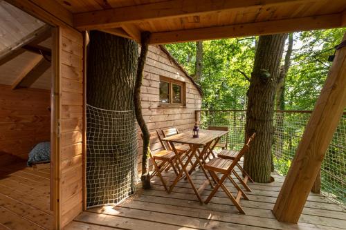 a wooden cabin with a table and chairs on a deck at Cabanes de la Grande Noe in Les Épasses