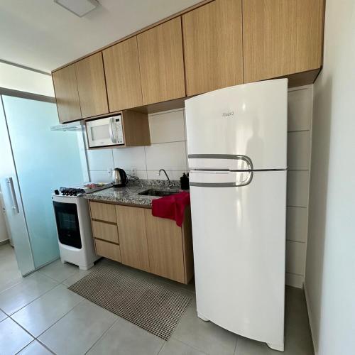 a kitchen with a white refrigerator and a stove at Flor Prime Loft in Extrema