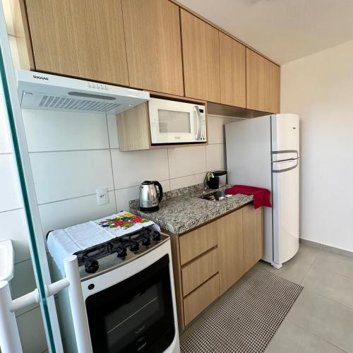 a small kitchen with a stove and a refrigerator at Flor Prime Loft in Extrema