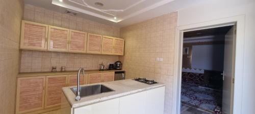 a kitchen with wooden cabinets and a sink at مساكن الخليج in Unayzah