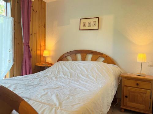 - une chambre avec un lit avec des draps blancs et 2 lampes dans l'établissement Appartement T2 cosy avec jardinet, proche centre et skibus, WiFi, parking et équipements complets - FR-1-624-61, à Samoëns