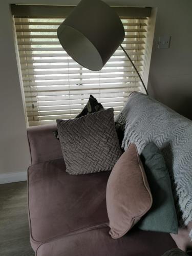 a couch with pillows and a lamp in a living room at Converted cattle barn overlooking Strangford Lough in Newtownards