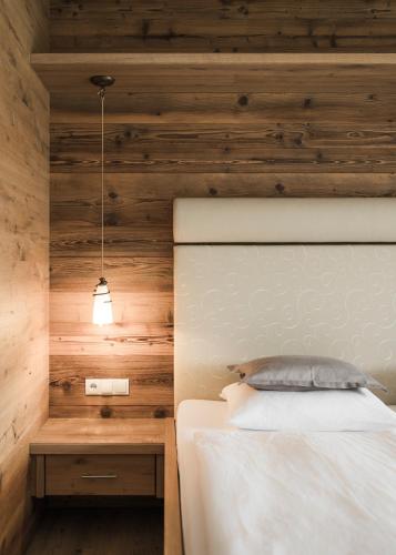 a bedroom with a bed with a wooden wall at Hotel Nussbaumerhof *** in Rodengo