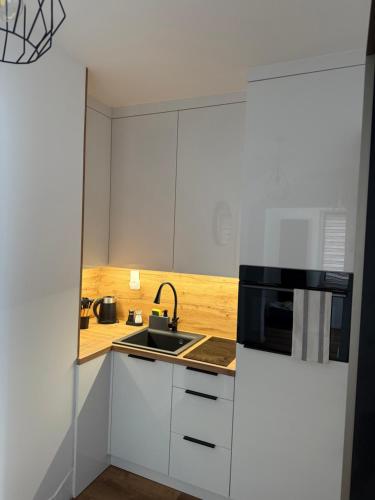 a white kitchen with a sink and a microwave at Apartament Grojec in Grojec