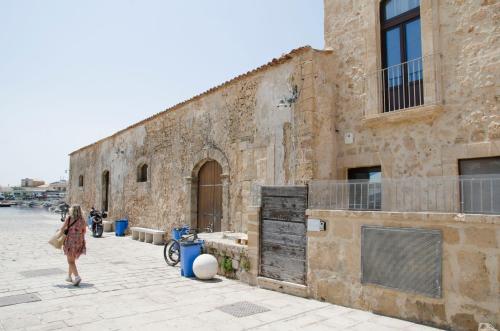 a woman walking down a street next to a brick building at La casa della Tonnara, Marzamemi in Marzamemi