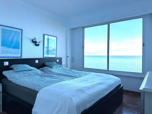 ein Schlafzimmer mit einem großen Bett mit zwei großen Fenstern in der Unterkunft Ferienwohnung am Strand - 2 Schlafzimmer in Arguineguín