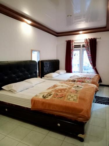 two beds sitting in a room with a window at Tulip Syariah 4 in Dieng