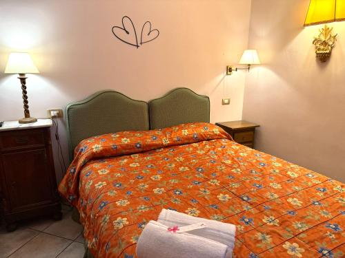a bedroom with a bed with a orange comforter at Villa Le Camelie Siena in Siena