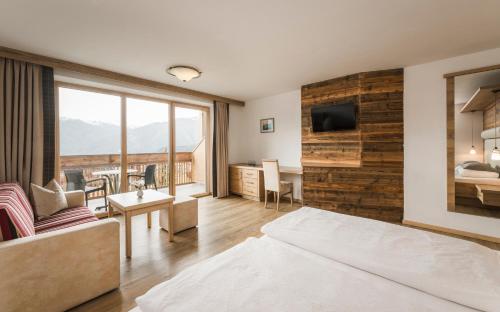 a bedroom with a bed and a living room with a view at Hotel Nussbaumerhof *** in Rodengo