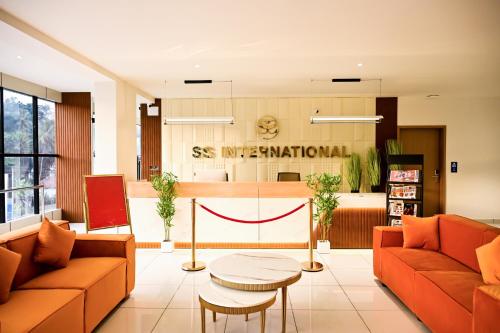 a lobby with two orange couches and a table at Hotel S S International Coorg in Suntikoppa