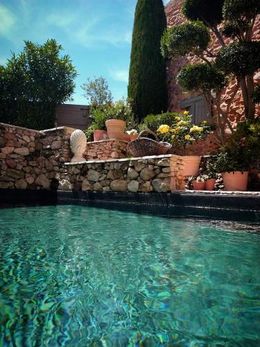 une piscine avec un mur en pierre et quelques plantes dans l'établissement Le mas de Roussillon, à Roussillon