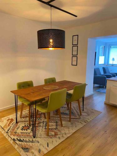 a dining room table with green chairs in a living room at Zwischen Mosel und Weinbergen in Mehring