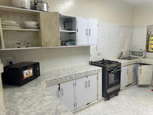 a kitchen with white cabinets and a stove in it at Sweet Mum in Malindi
