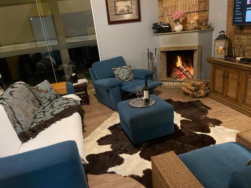 a living room with blue chairs and a fireplace at Paradise for your family next to Porto Alegre in Eldorado do Sul
