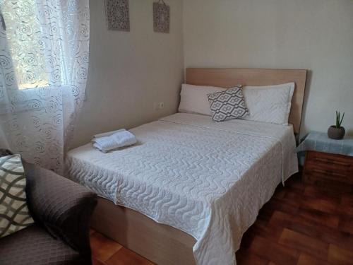 a bedroom with a bed with a white comforter and a window at Argy close to the center in Asprovalta