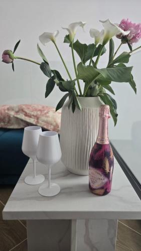 a table with a vase with flowers and a vase at Villa Marmont Karlovac Luksuzni Smještaj na Top Lokaciji s Parkingom i Self Check inom in Karlovac