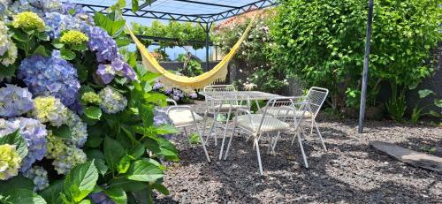 a table and chairs in a garden with purple flowers at Casa da Ponta in Ponta do Pargo