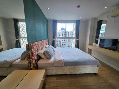 ein Schlafzimmer mit einem Bett und einem Tisch und Fenstern in der Unterkunft Stunning 1bdr in Fairytale Water park Condo Grande Caribbean in Pattaya South