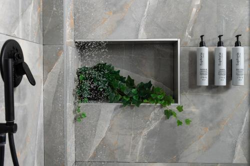 a wall with a niche with a plant and three bottles at Heaven Hotel Thessaloniki Airport in Néon Rýsion