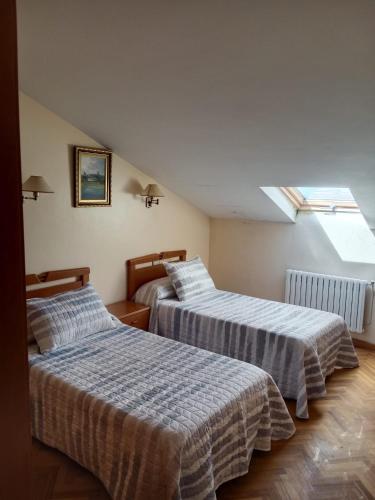 two beds in a room with a window at Hostal Acantilado in Villadaíde