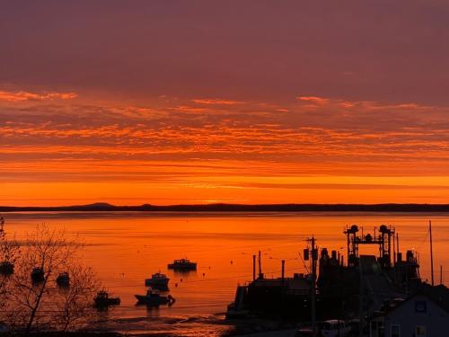 Una puesta de sol sobre un cuerpo de agua con barcos. en Eco-friendly studio - ocean views, close to beach, en Lincolnville