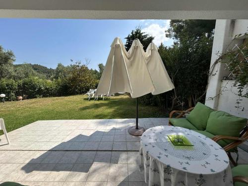 a patio with a table and an umbrella at Villa Georgia Poseidi in Kalandra