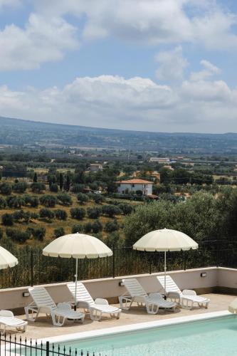 a pool with white chairs and umbrellas and a view at Villa Olivieri B&B Wellness House in Viterbo