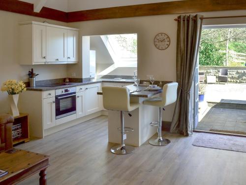 a kitchen with white cabinets and a table and chairs at Little Hoot in Baslow