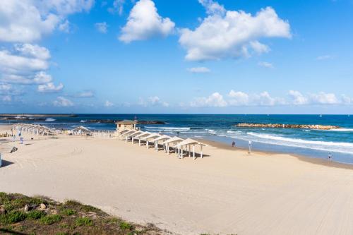 a beach with rows of umbrellas and the ocean at Sea View Stylish 1BR with Balcony by Beachfront Stay in Herzelia 