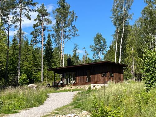 a cabin in the woods with a gravel road in front at Sukha Nordic Retreats in Arvika