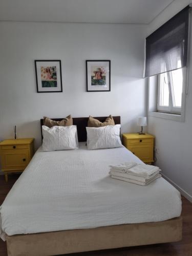 a bedroom with a large bed with white sheets and a window at Oporto Seaside Village - Casa Quinta in Matosinhos