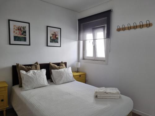 a bedroom with a bed with white sheets and a window at Oporto Seaside Village - Casa Quinta in Matosinhos
