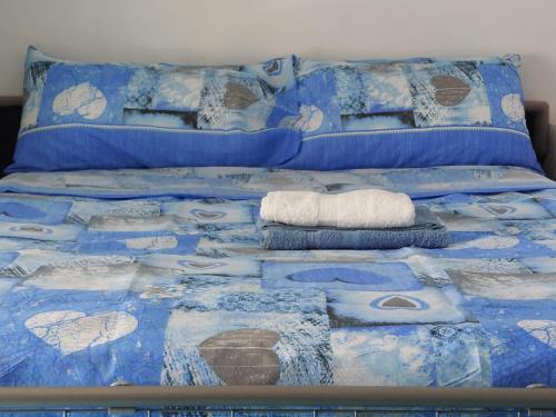 a bed with blue and white sheets and pillows at Casa Blu with Sea View - Borgo Stays in Sperlonga