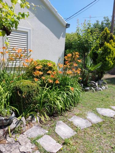 a garden with flowers next to a house at Holiday Home Sunrise in Gruda