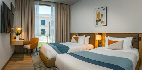 a hotel room with two beds and a desk at First Grand Hotel in Dammam