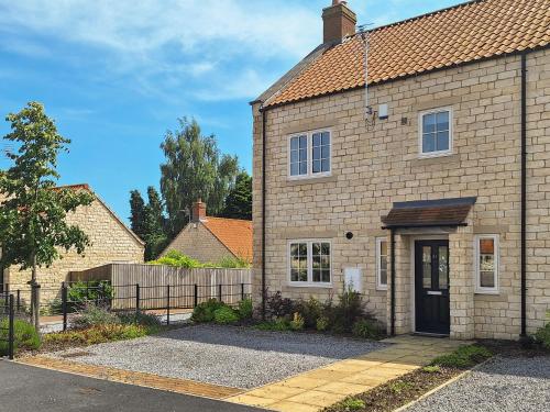 a brick house with a black door and a fence at The Garth in Helmsley