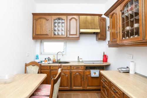 a kitchen with wooden cabinets and a wooden table at Guest House MICAJ in Himare