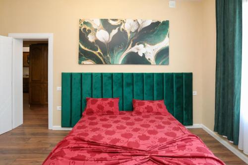 a bedroom with a red bed with a green headboard at Guest House MICAJ in Himare