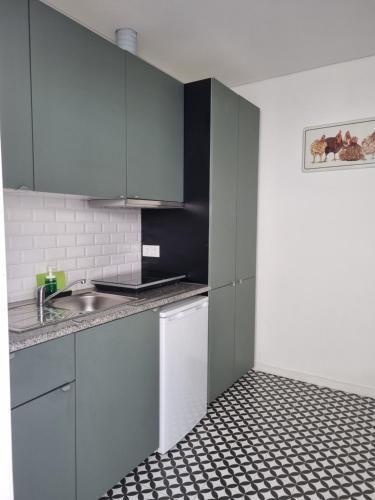 una cucina con armadietti bianchi e pavimento piastrellato bianco e nero. di Oporto Seaside Village - Casa Quinta a Matosinhos