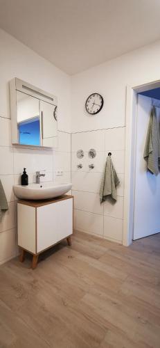 a bathroom with a sink and a clock on the wall at LandRäume barrierefrei in Lunden