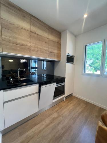 une cuisine avec des comptoirs blancs et noirs et une fenêtre dans l'établissement Appartement Prestige 6 à 10pers I Draps&ménage inclus I parking privé, à Saint-Lary-Soulan