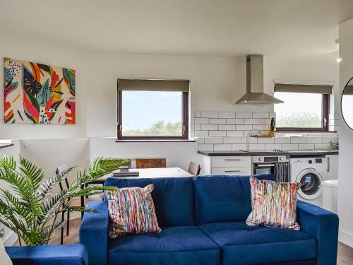 een woonkamer met een blauwe bank in een keuken bij Sandymouth Cottage in Marhamchurch