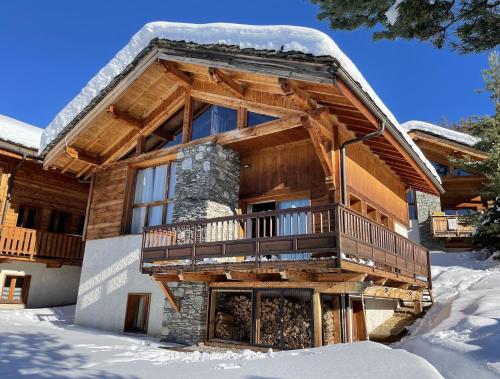 une cabane en rondins dans la neige avec un balcon dans l'établissement Chalet ALPACA Peisey-Vallandry - Domaine Paradiski, à Peisey-Nancroix