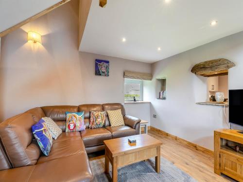a living room with a brown leather couch and a table at Middlecroft - Uk45062 in Tideswell
