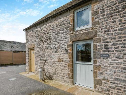 a brick building with a white door and a window at Middlecroft - Uk45062 in Tideswell