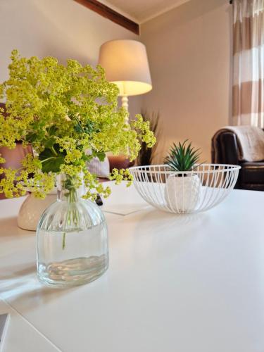 a vase with flowers on a table with two bowls at Ferienwohnung Hein sien Huus Rodenäs Nordfriesland in Rodenäs
