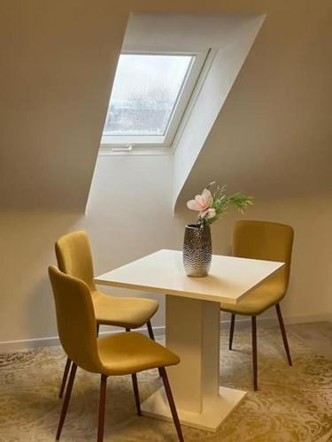 a table with chairs and a vase with flowers on it at Singel Apartment Wohnen auf Zeit in Hirschaid